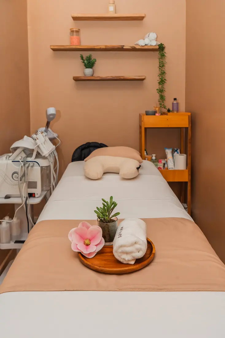 La cabine de soin : table de massage, serviettes roulées et fleur