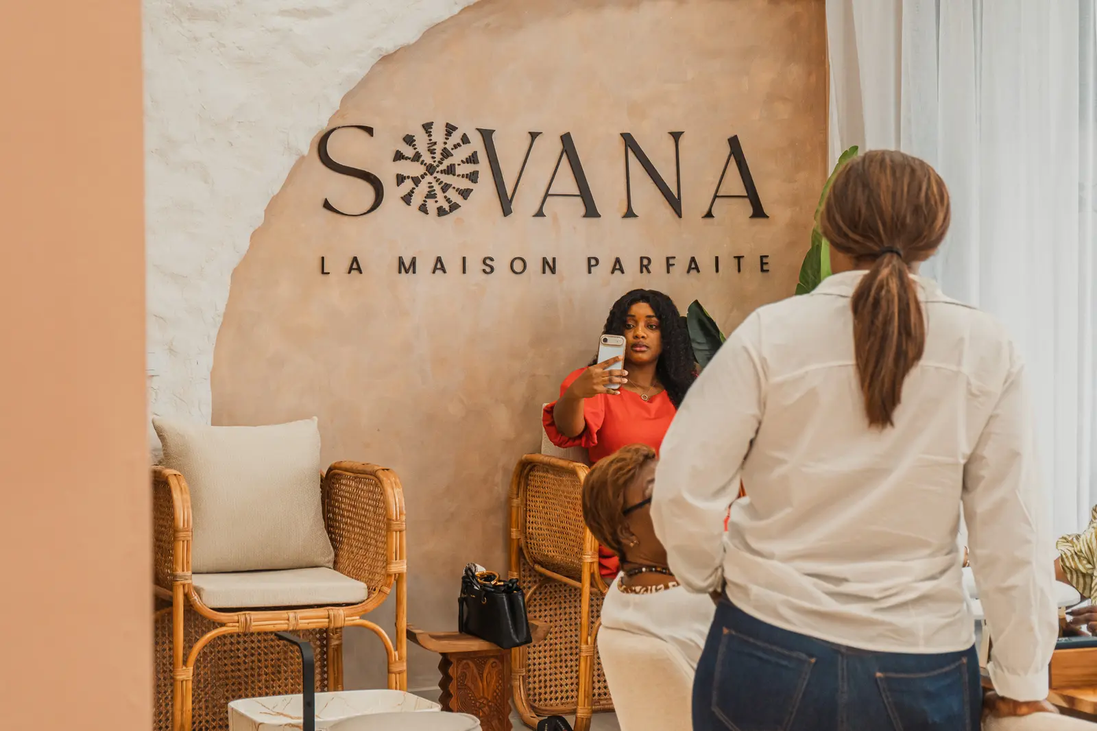 Une cliente accueillie dans le salon, devant le mur logo